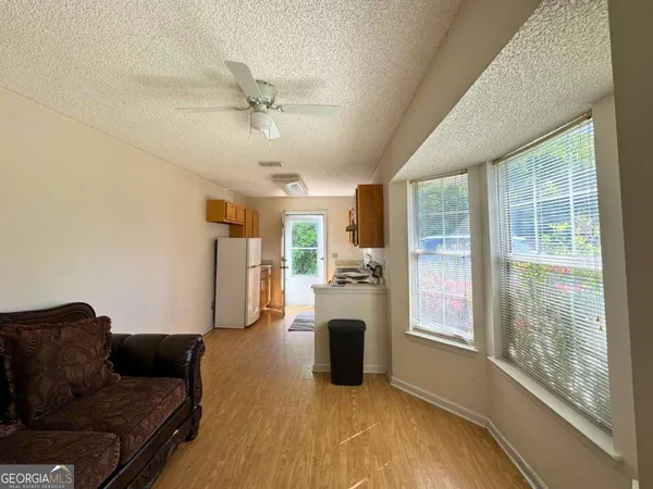 a living room with furniture floor to ceiling window and refrigerator