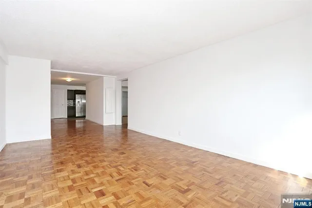 a view of an empty room and kitchen