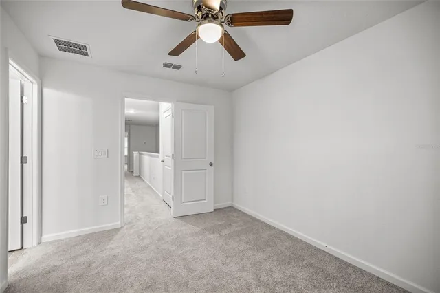 an empty room with closet and a ceiling fan