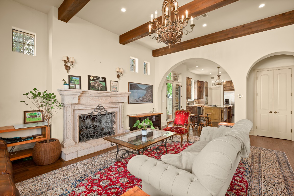 Living area with a chandelier, arched walkways, wood finished floors, recessed lighting, and a high end fireplace