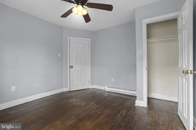 an empty room with wooden floor cabinet and a ceiling fan