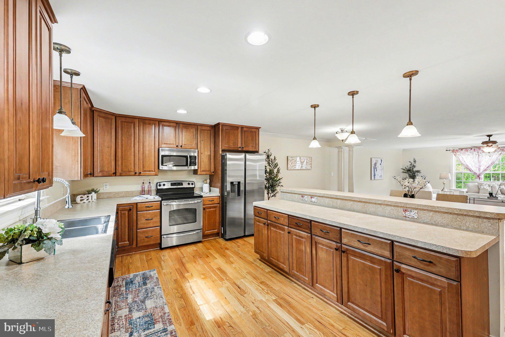 1564 Perry Road Winchester, VA 22602 - Photo 12 of 42 a large kitchen with stainless steel appliances kitchen island granite countertop a sink counter space and wooden floor