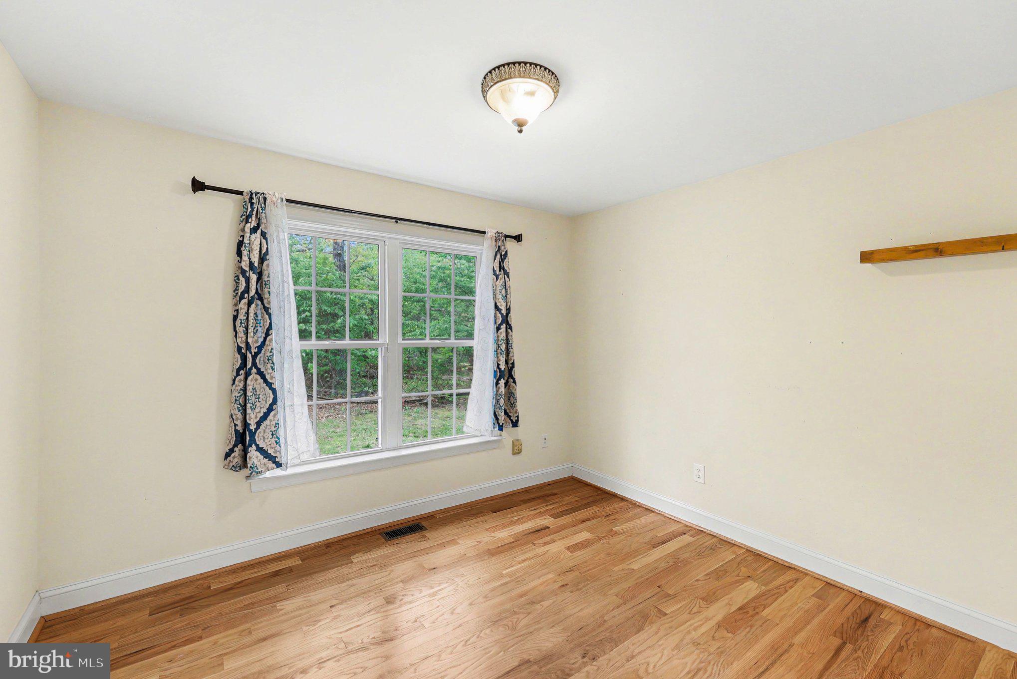 1564 Perry Road Winchester, VA 22602 - Photo 19 of 42 a view of an empty room with wooden floor and a window