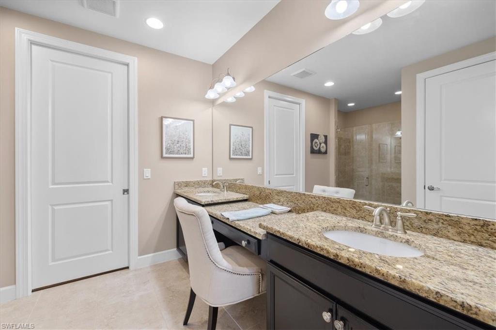 9684 Montelanico Loop, Unit 102 Naples, FL 34119 - Photo 16 of 24 a bathroom with a granite countertop sink a mirror and a vanity