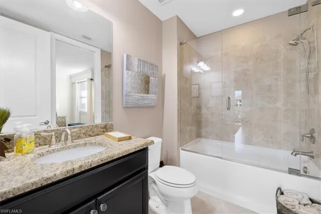 a bathroom with a granite countertop bathtub sink vanity mirror and toilet