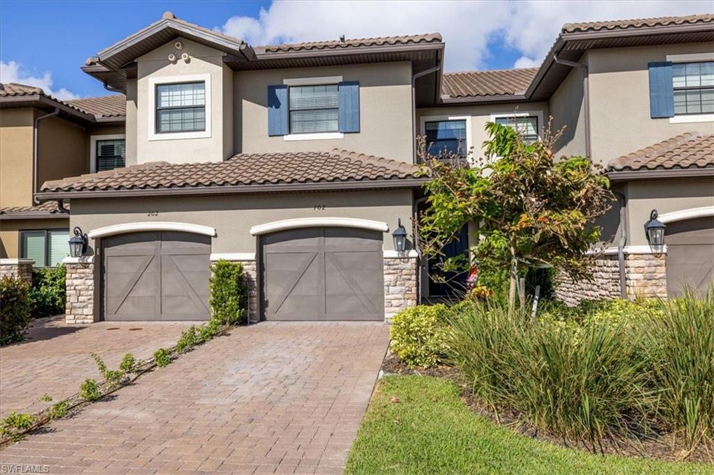 9684 Montelanico Loop, Unit 102 Naples, FL 34119 - Photo 22 of 24 a front view of a house with garden
