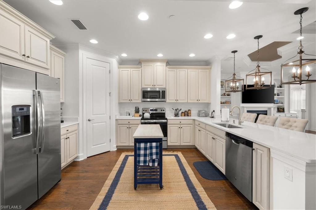 9684 Montelanico Loop, Unit 102 Naples, FL 34119 - Photo 3 of 24 a kitchen with stainless steel appliances kitchen island granite countertop a refrigerator sink and cabinets
