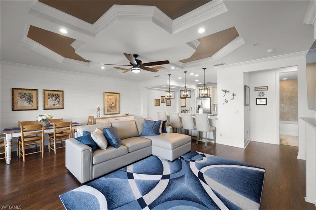 9684 Montelanico Loop, Unit 102 Naples, FL 34119 - Photo 6 of 24 a living room with furniture a wooden floor and a chandelier