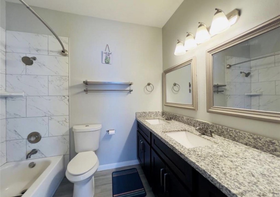 3800 Tanglewilde Street West, Unit 806 Houston, TX 77063 - Photo 6 of 12 a bathroom with a granite countertop toilet sink and mirror