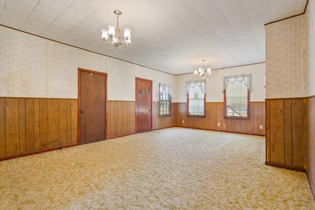 a view of a livingroom with a chandelier fan and kitchen view