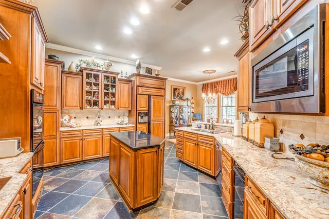 a large kitchen with stainless steel appliances granite countertop a sink and wooden cabinets
