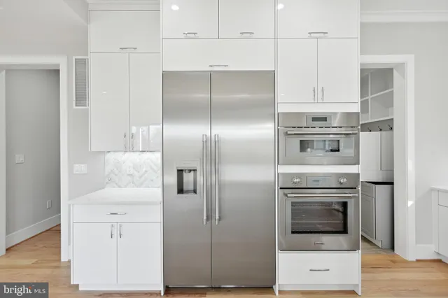a large white kitchen with a sink and dishwasher next to a large window