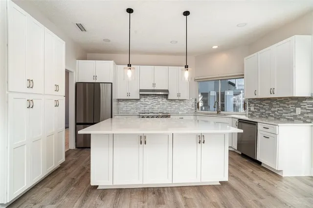 a kitchen with kitchen island white cabinets and refrigerator