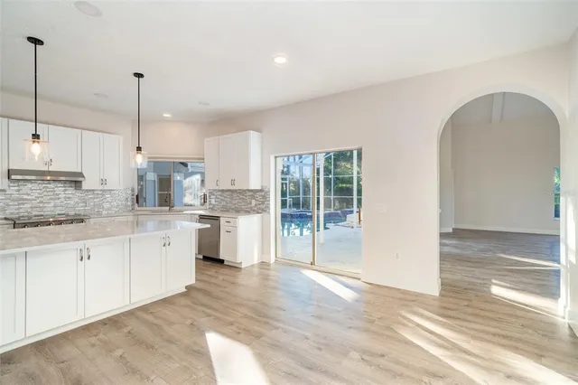 a open kitchen with granite countertop a stove top oven a sink a counter space and cabinets