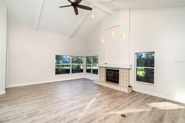 an empty room with fireplace wooden floor and windows