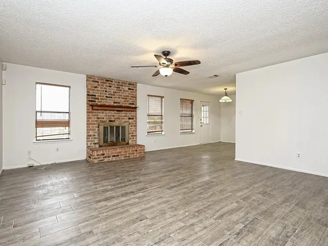 an empty room with windows and fireplace