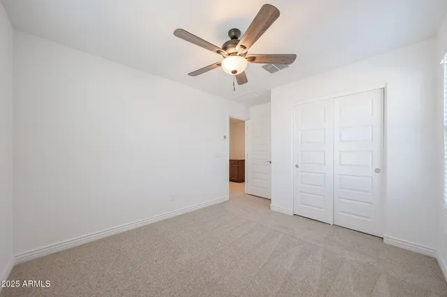 an empty room with closet and ceiling fan