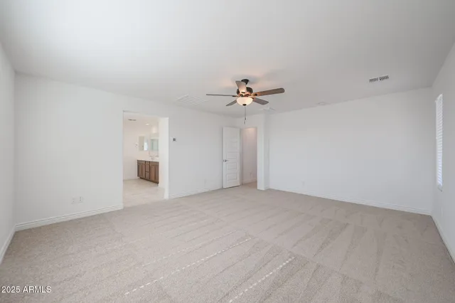 a view of an empty room with chandelier fan