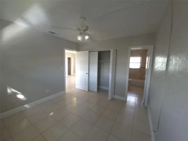 an empty room with chandelier fan and windows