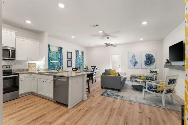 a large white kitchen with stainless steel appliances granite countertop a stove and a wooden floors