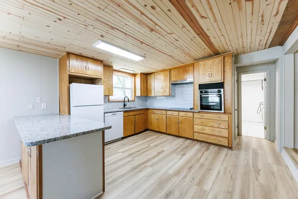 a kitchen with stainless steel appliances granite countertop a sink dishwasher a stove and refrigerator with wooden floor