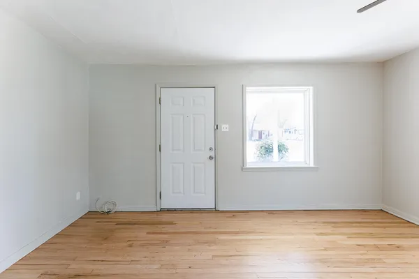 a view of an empty room with wooden floor and a window