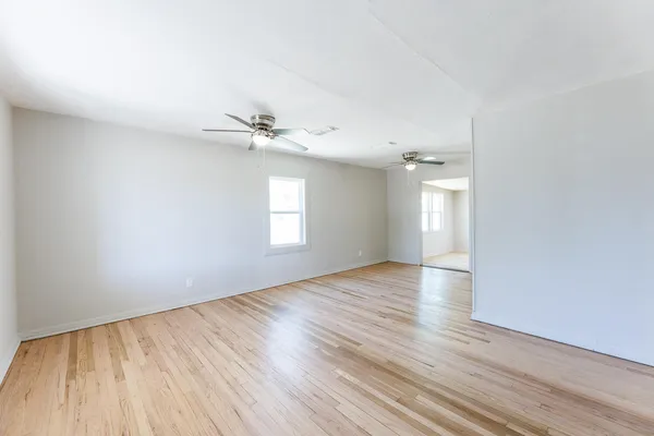 a view of an empty room with a window and wooden floor