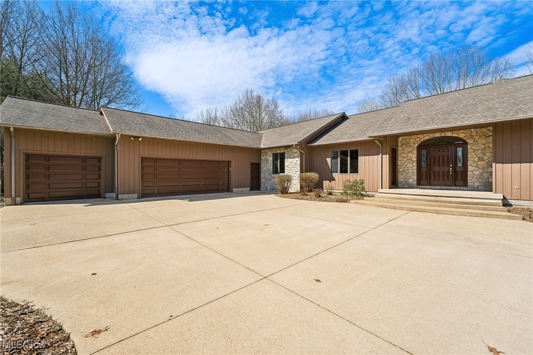 43301 Parsons Road Oberlin, OH 44074 - Photo 37 of 47 View of front of property featuring concrete driveway, stone siding, board and batten siding, an attached garage, and a shingled roof