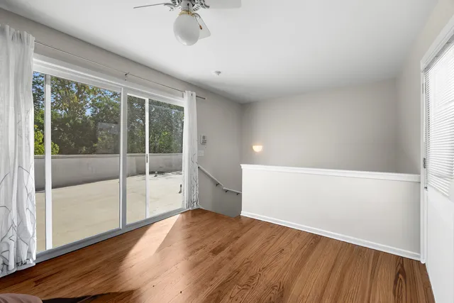 a view of empty room with wooden floor and fan