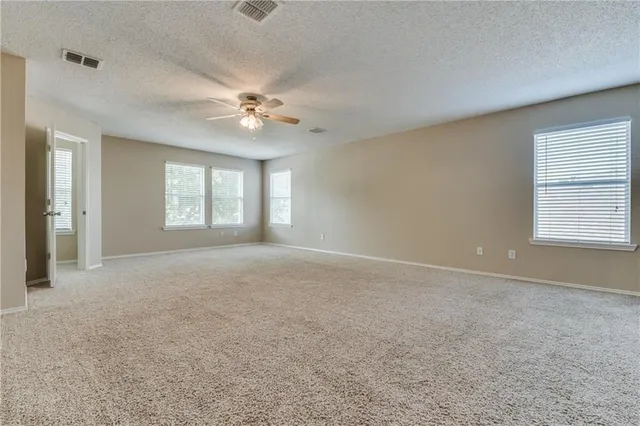 an empty room with windows and ceiling fan