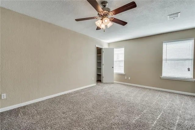 an empty room with windows and fan