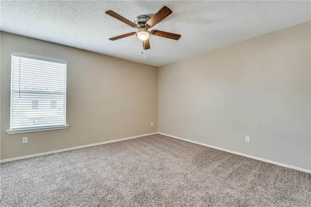 an empty room with a window and a ceiling fan