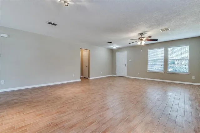 a view of an empty room with a window and wooden floor