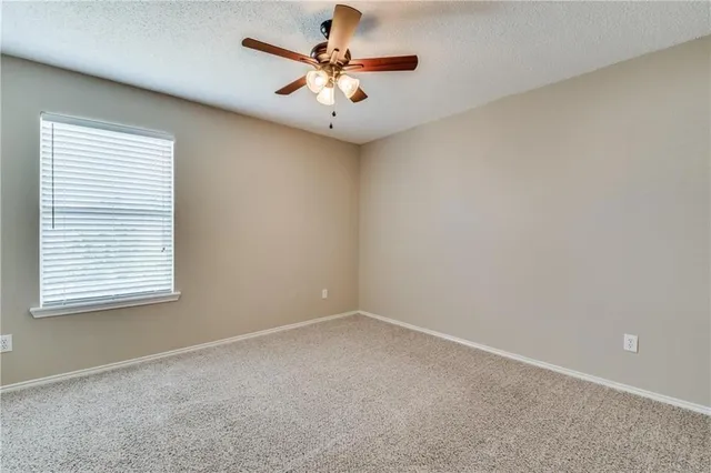 an empty room with a window and a ceiling fan