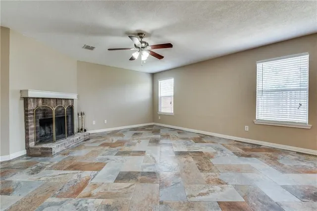 a view of an empty room with window and chandelier fan