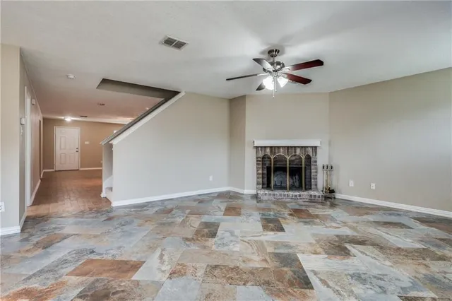 a view of an empty room with a ceiling fan and window