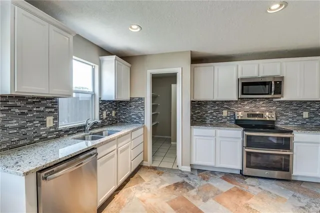 a kitchen with stainless steel appliances granite countertop a stove a sink and a microwave