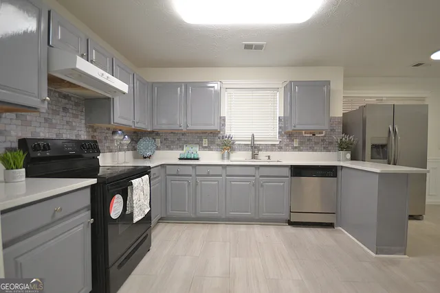 a kitchen with kitchen island granite countertop a sink cabinets and stainless steel appliances