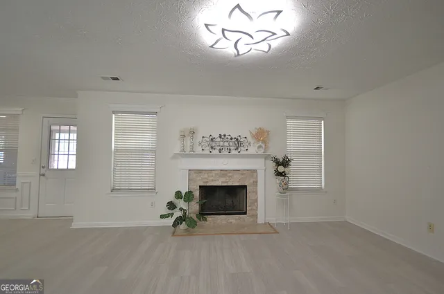 an empty room with windows fireplace and wooden floor