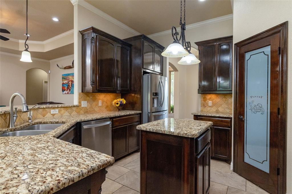 208 Ellis Creek Drive Weatherford, TX 76085 - Photo 17 of 40 a kitchen with kitchen island granite countertop a sink and a refrigerator