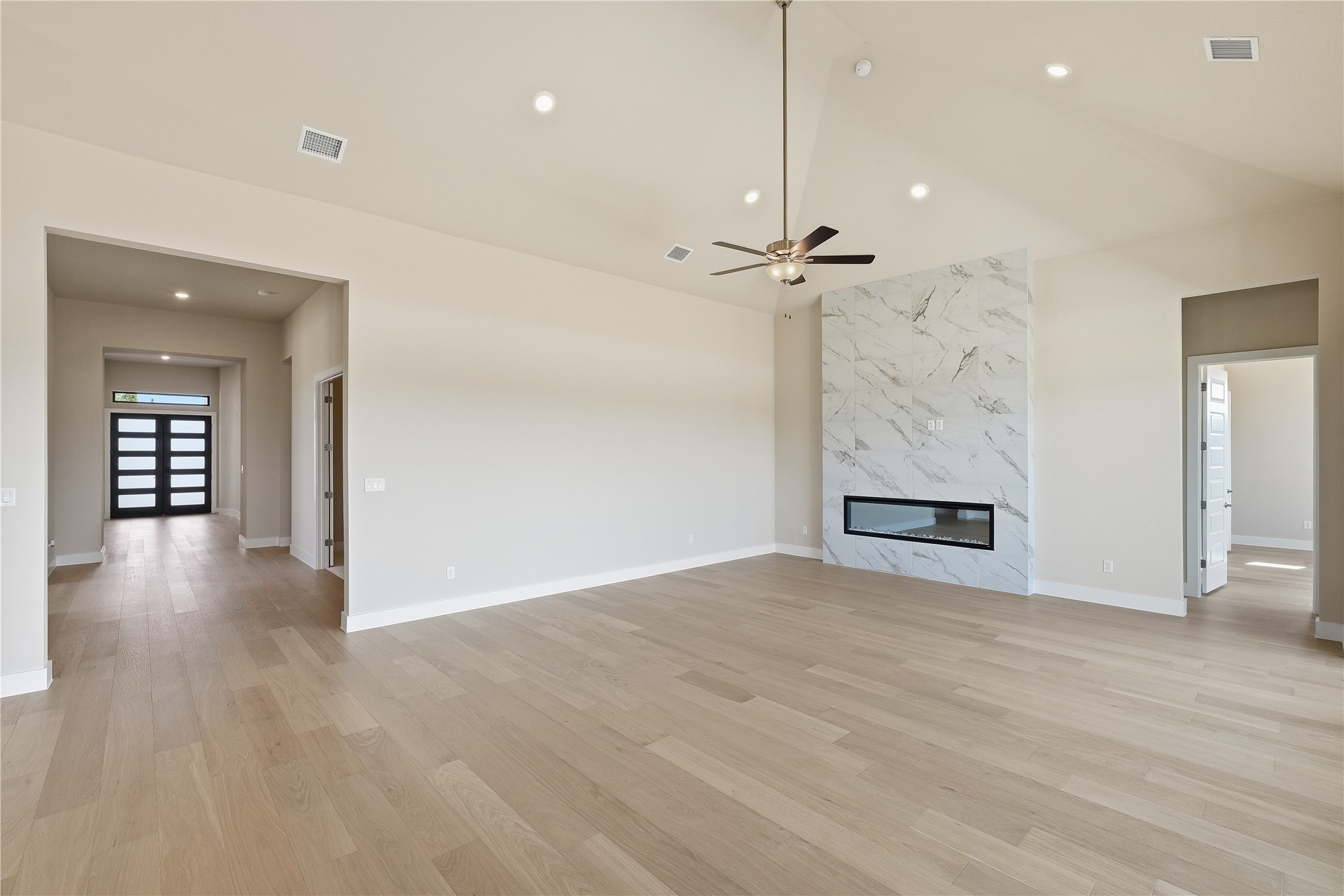 1209 Doelling Drive Georgetown, TX 78633 - Photo 4 of 31 Unfurnished living room with a premium fireplace, ceiling fan, light wood-type flooring, recessed lighting, and lofted ceiling