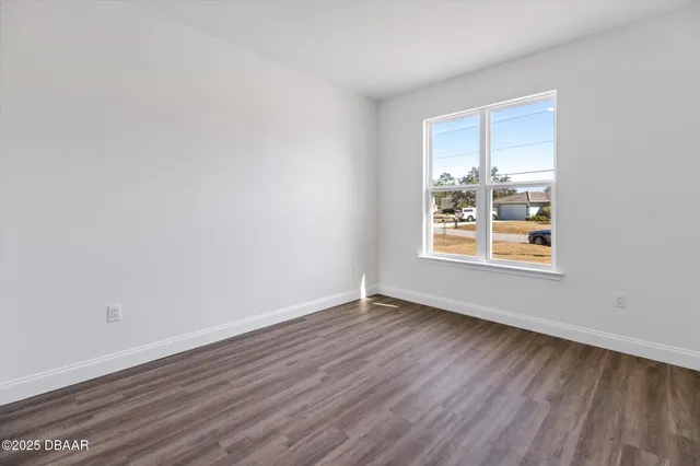 a view of an empty room with wooden floor and closet