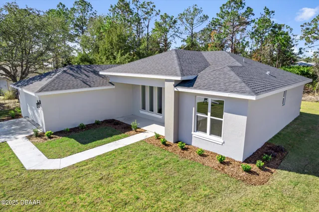 a aerial view of a house with yard and trees in the background