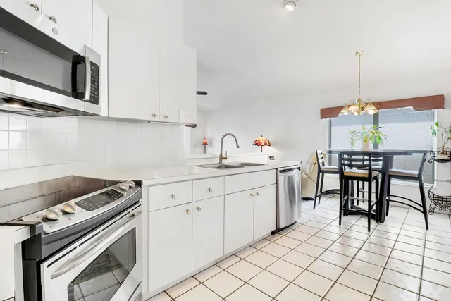 a kitchen with stainless steel appliances a stove a sink and white cabinets