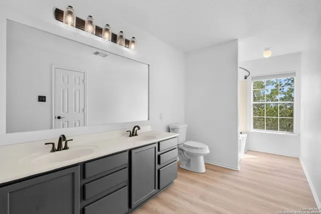 a bathroom with a double vanity sink toilet and a tub