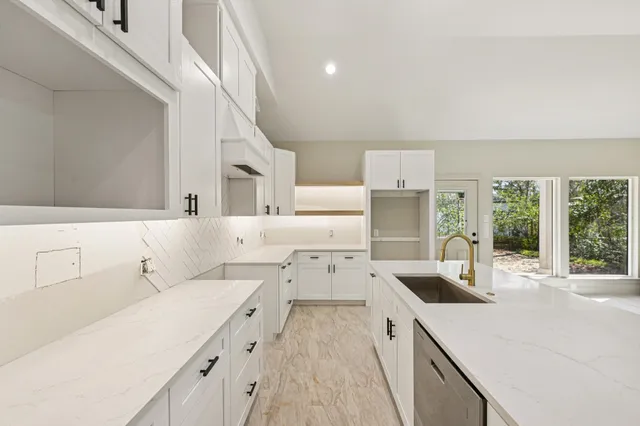 a kitchen with a sink dishwasher and white cabinets with wooden floor