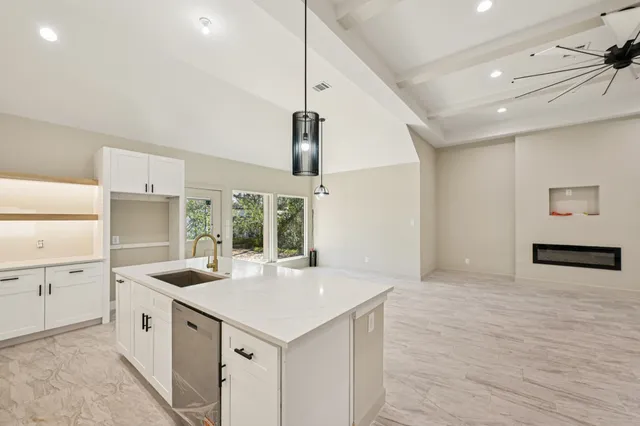 a large white kitchen with a sink and dishwasher with wooden floor