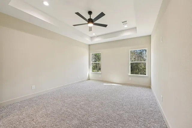an empty room with ceiling fan and windows