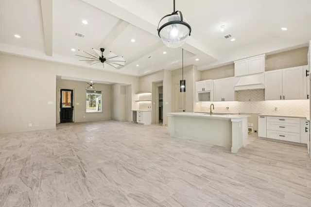 a large white kitchen with a refrigerator a stove and a chandelier