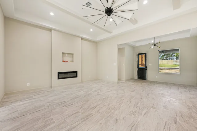 a view of an empty room with a window and kitchen view